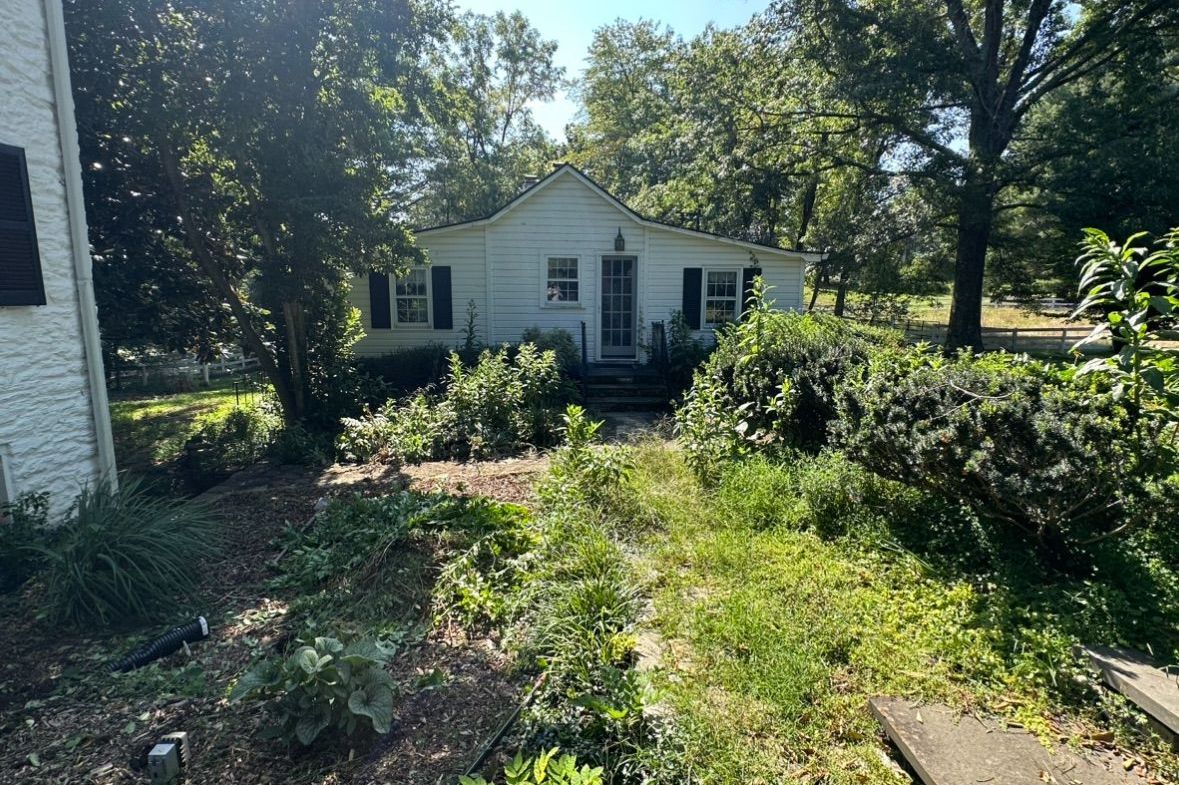 A white house with a lush green yard in front of it.