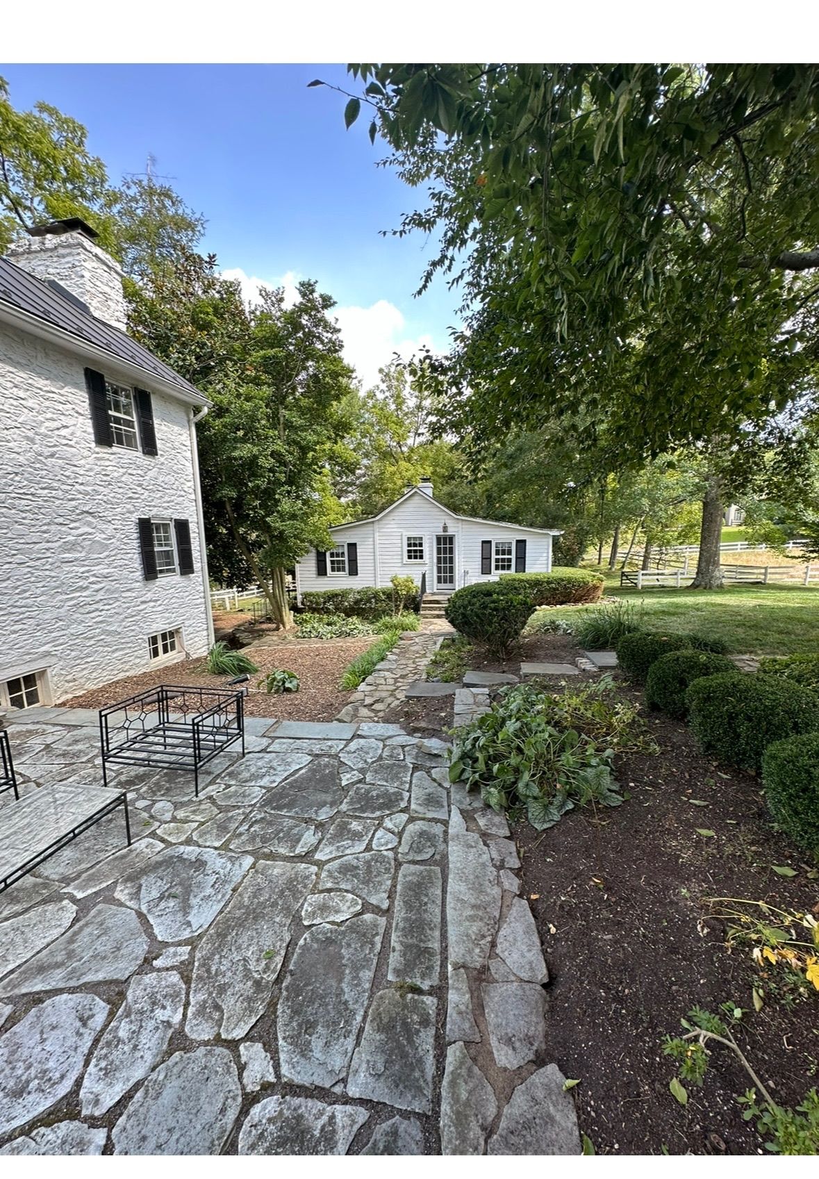A white brick house with a stone patio in front of it.