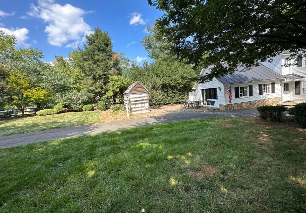 A large white house with a wooden shed in front of it.