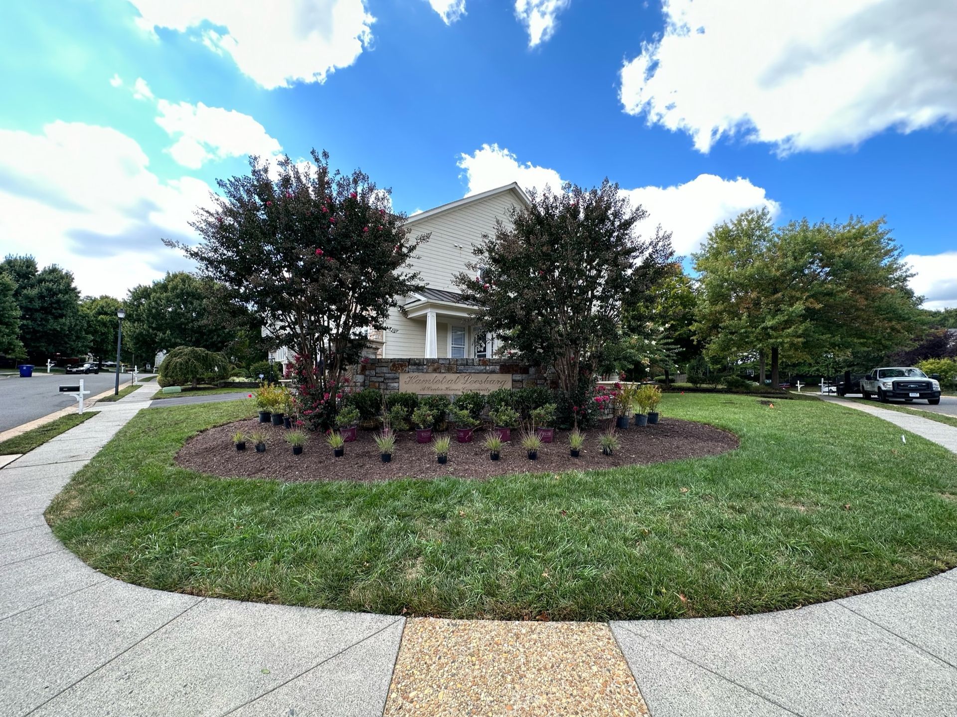 A white house with a circular lawn in front of it.