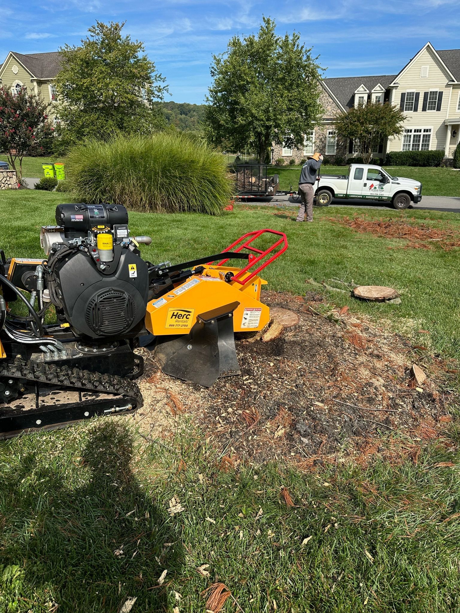 A stump grinder is cutting a tree stump in a yard.