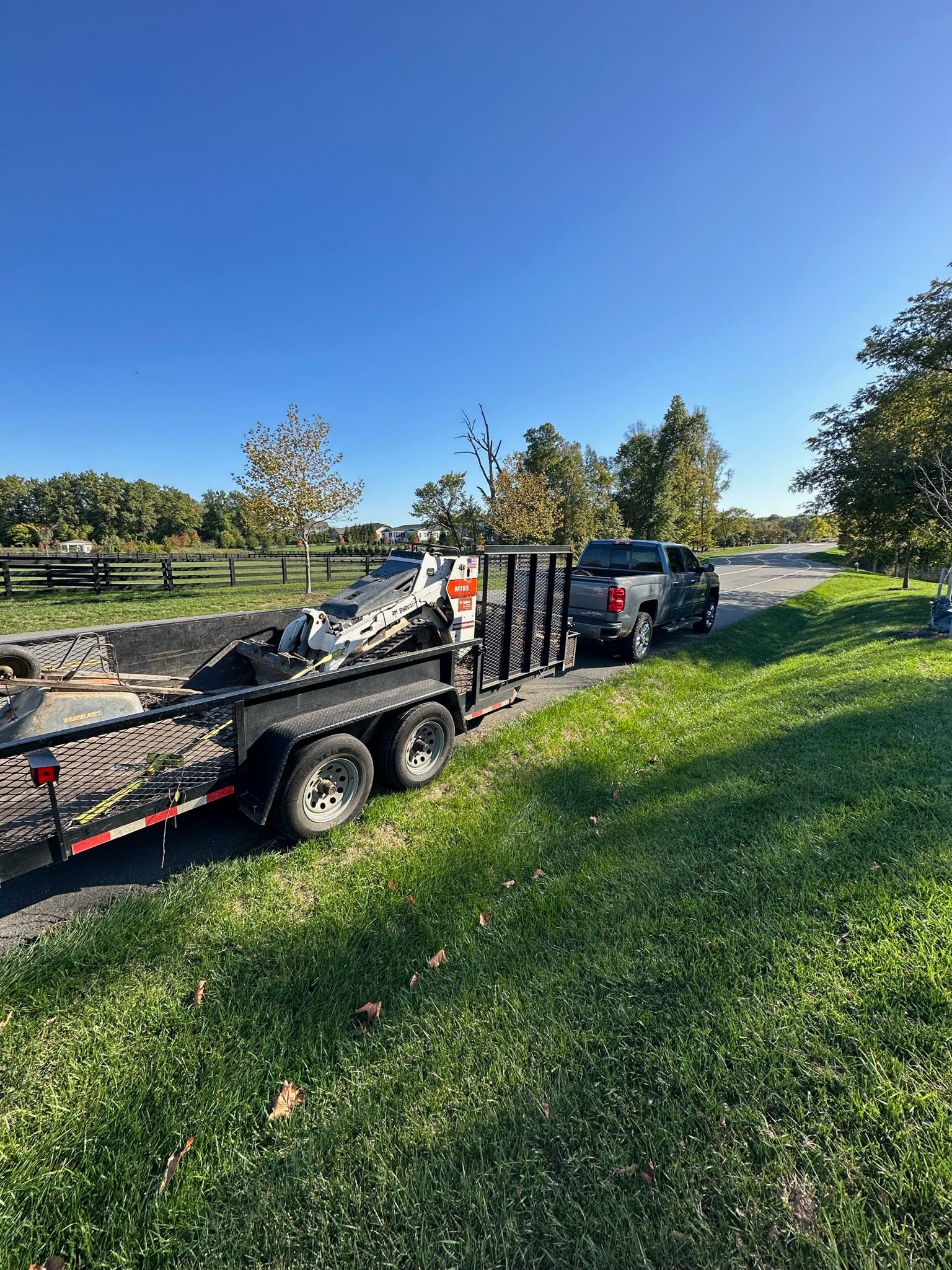 A truck is towing a trailer with a motorcycle on it.