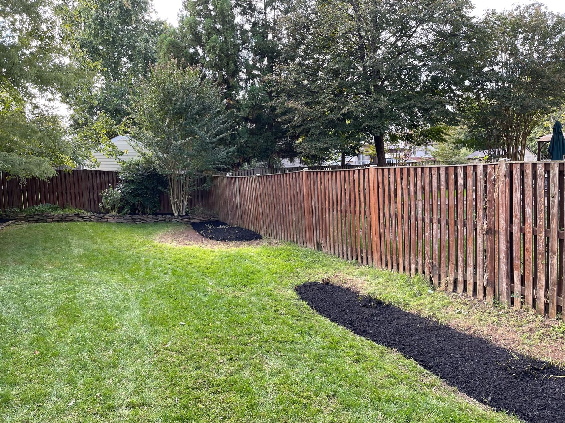 A wooden fence surrounds a lush green yard.