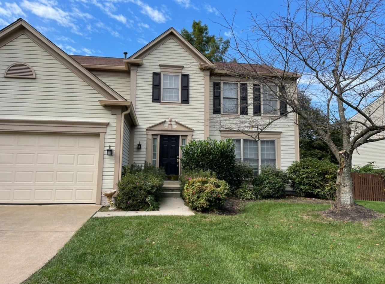 A large house with a garage and a tree in front of it.