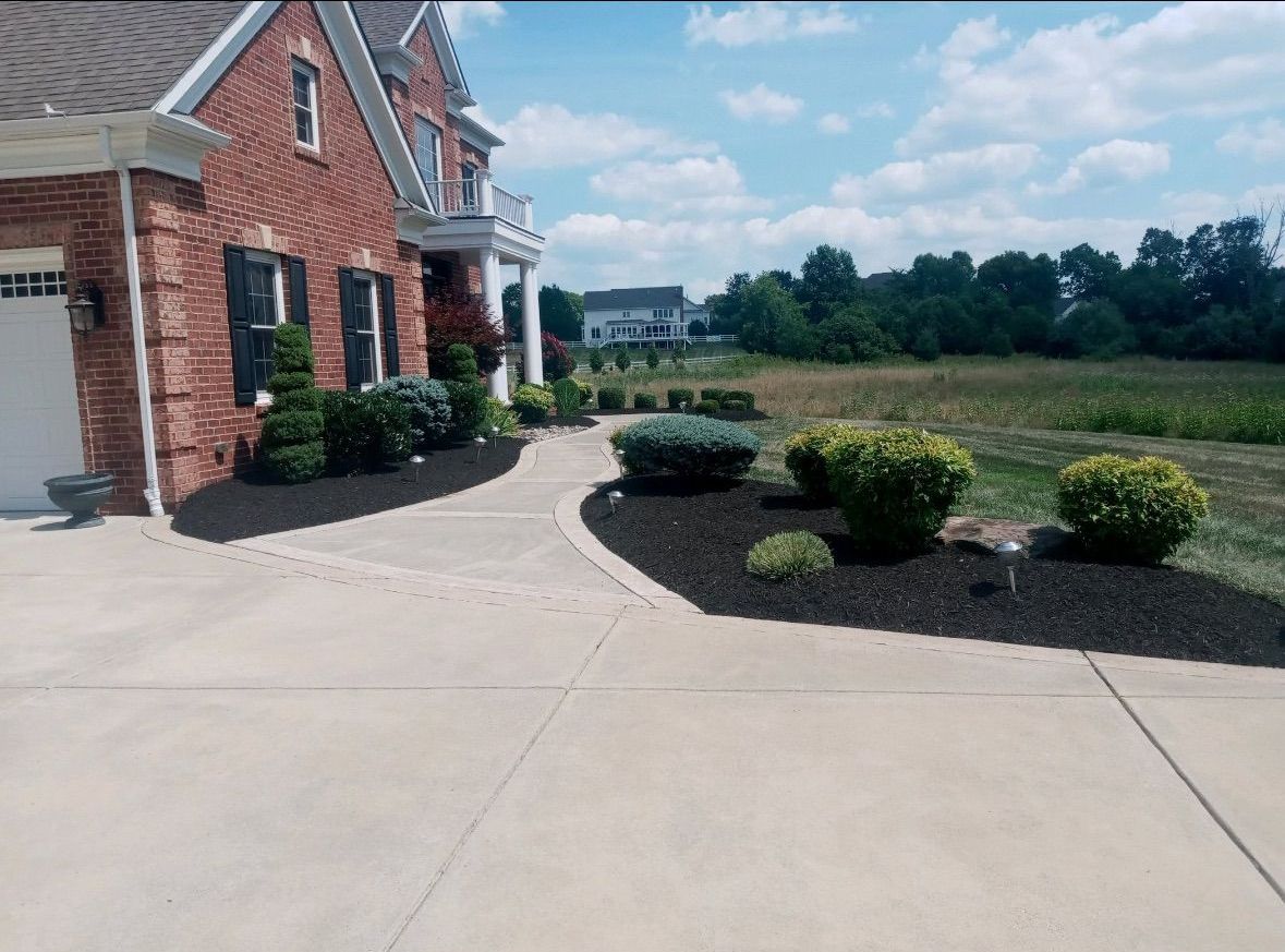 A large brick house with a concrete driveway leading to it.