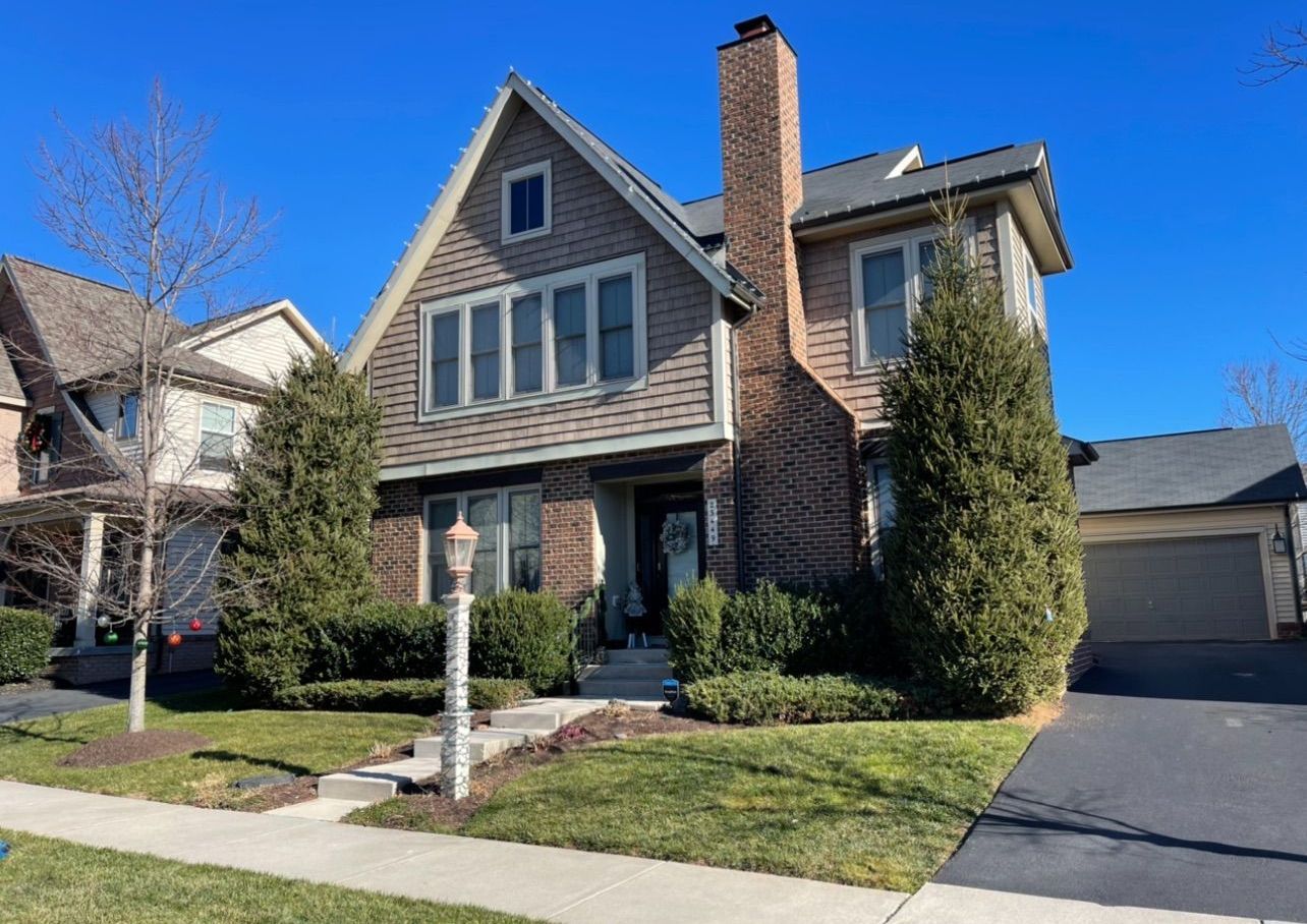 A large brick house with a chimney is sitting on a lush green lawn.