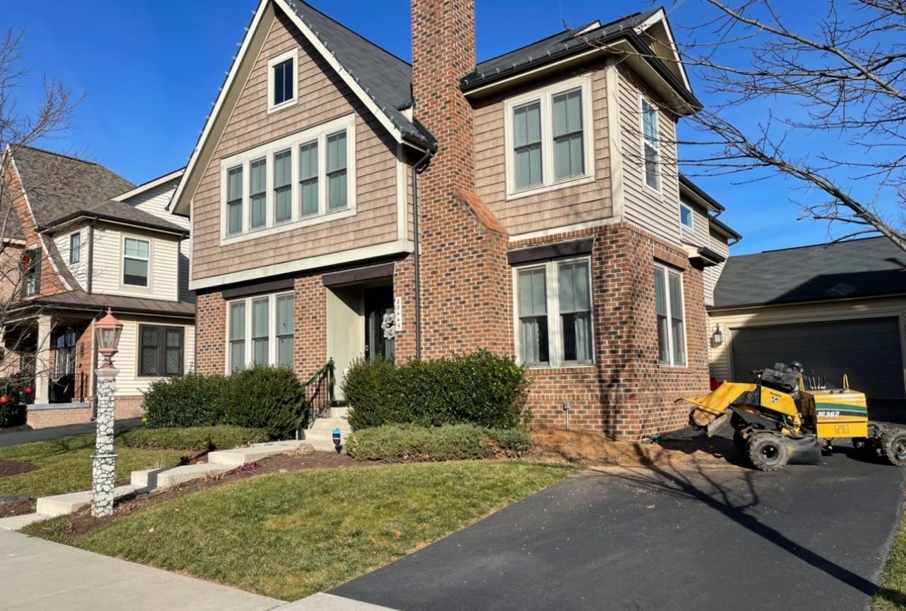 A large brick house with a lawn mower parked in front of it.