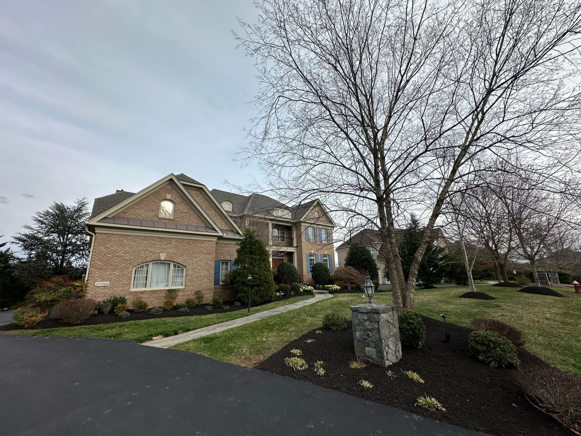 A large brick house with a tree in front of it.