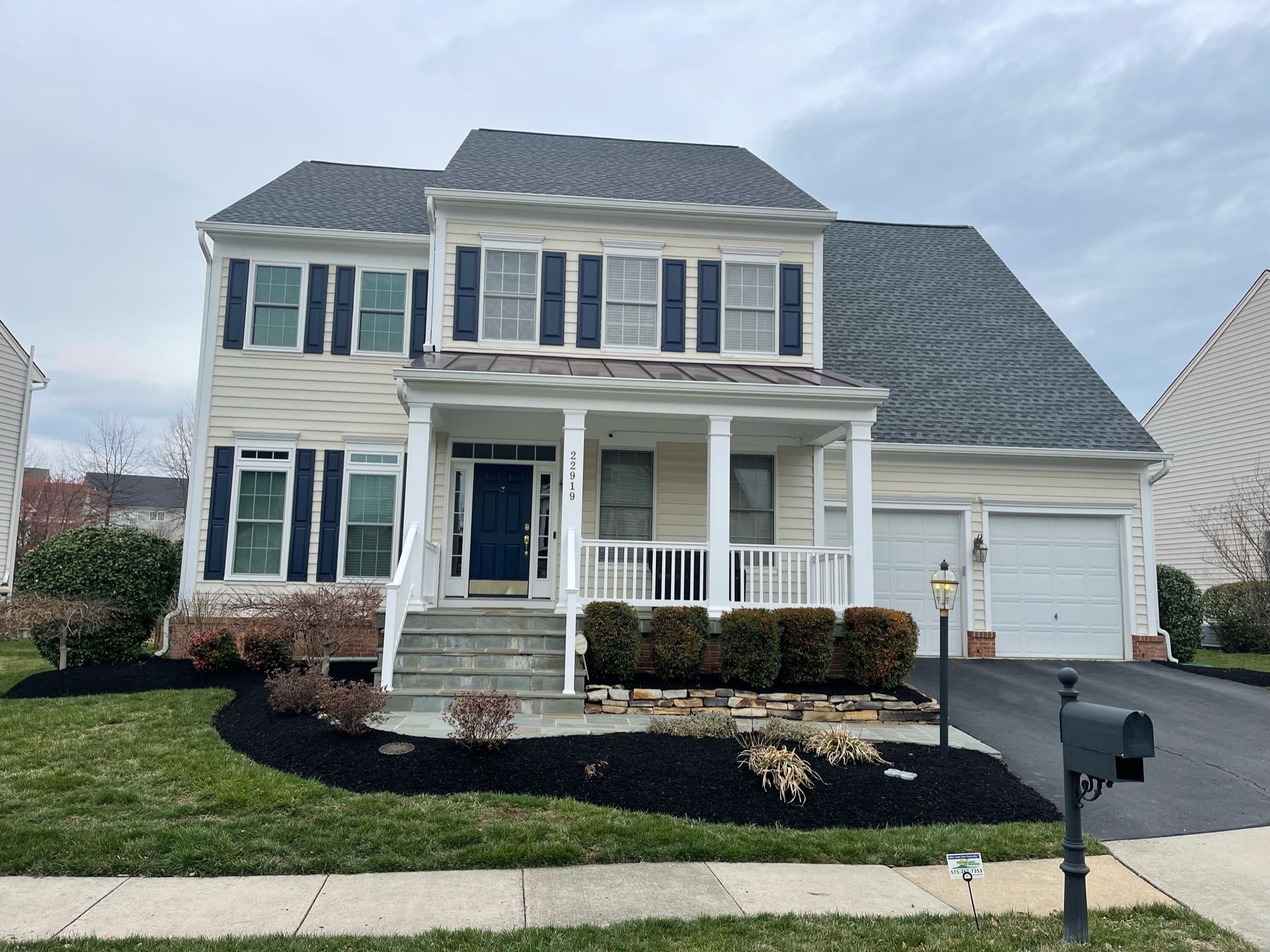 A large white house with blue shutters and a mailbox in front of it.
