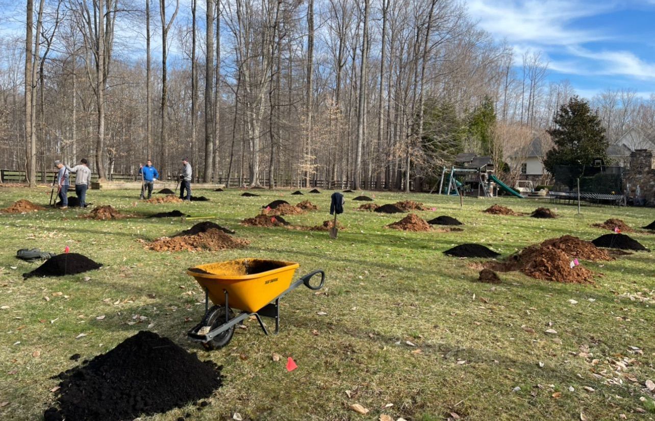 A wheelbarrow filled with dirt is sitting in the middle of a grassy field.