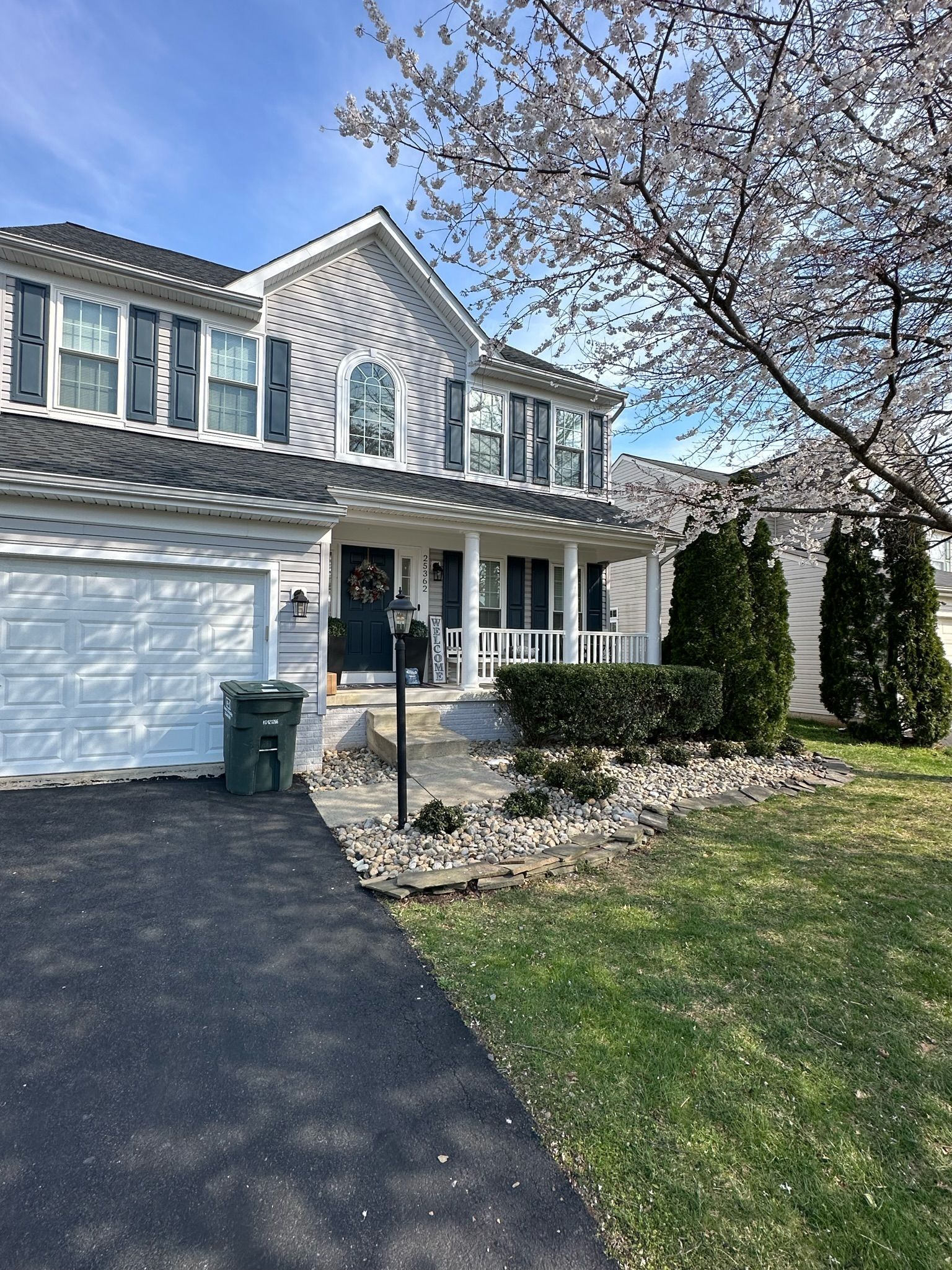 A large white house with a cherry blossom tree in front of it