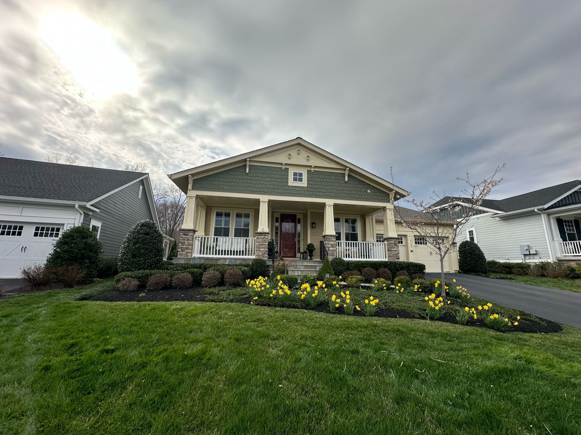 A house with a green roof is sitting on top of a lush green lawn.