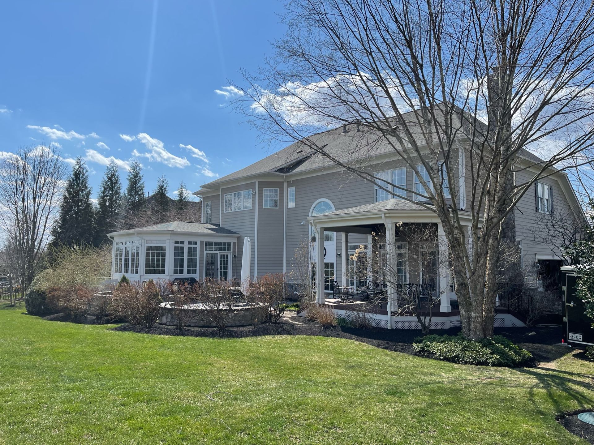 A large house with a porch and a large lawn in front of it.