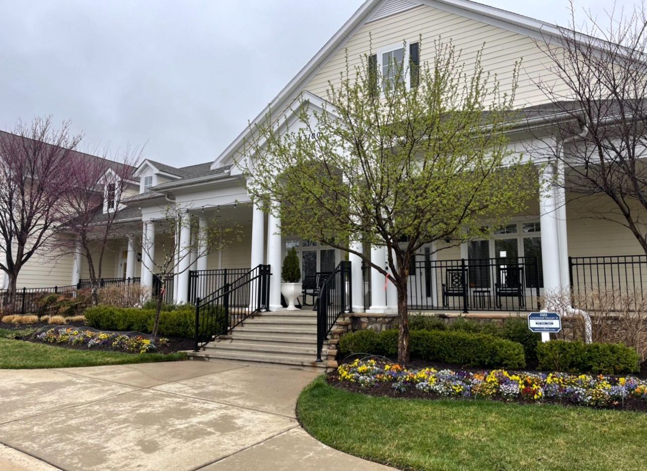 A large white house with a porch and stairs in front of it.
