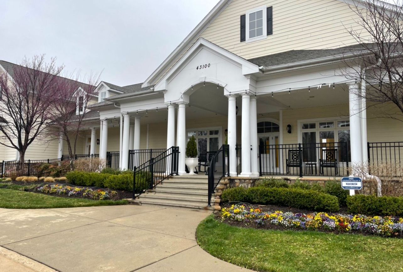 A large white house with a large porch and stairs leading to it.
