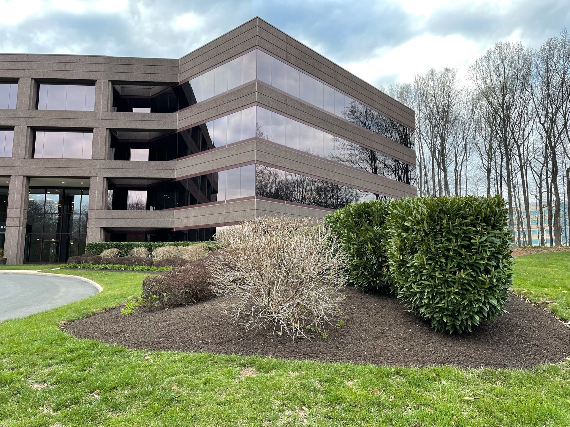 A large building with a lot of windows is surrounded by trees and grass.