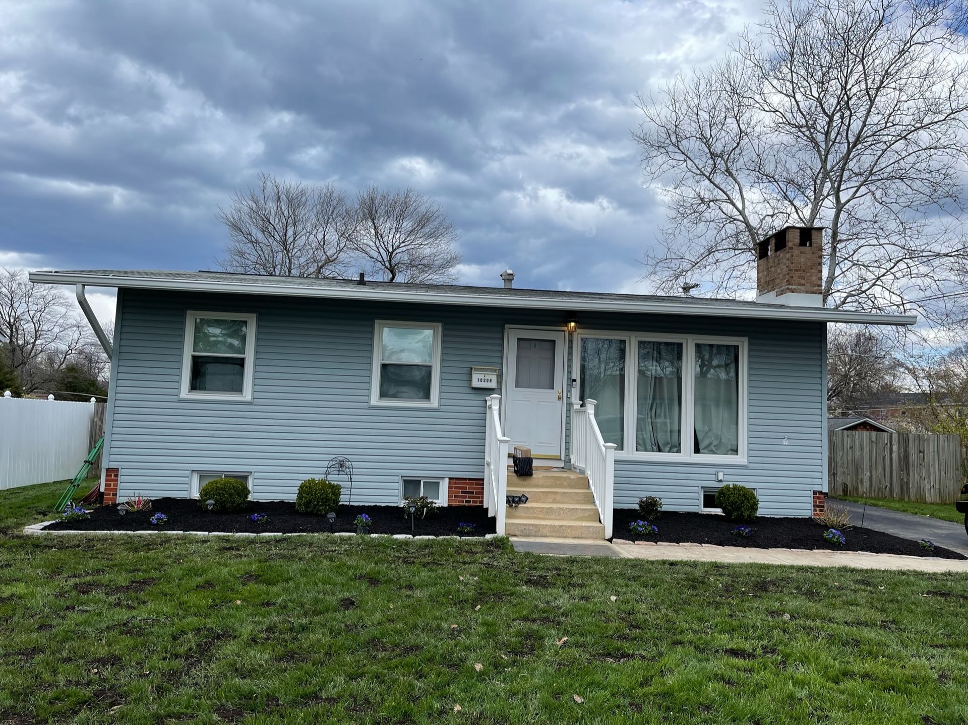 A small house with stairs leading up to the front door is sitting on top of a lush green lawn.