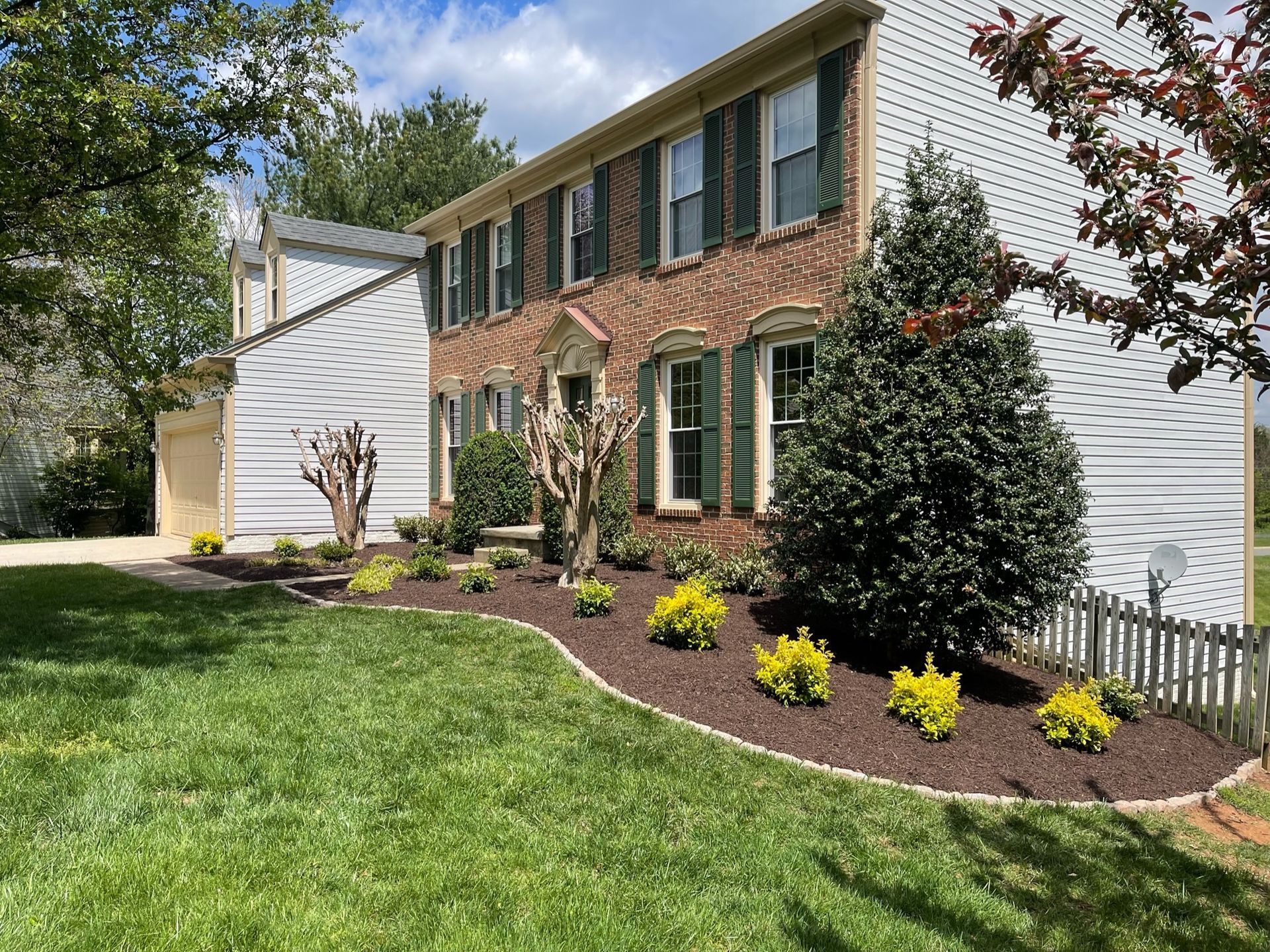 A large brick house with a lush green lawn in front of it.