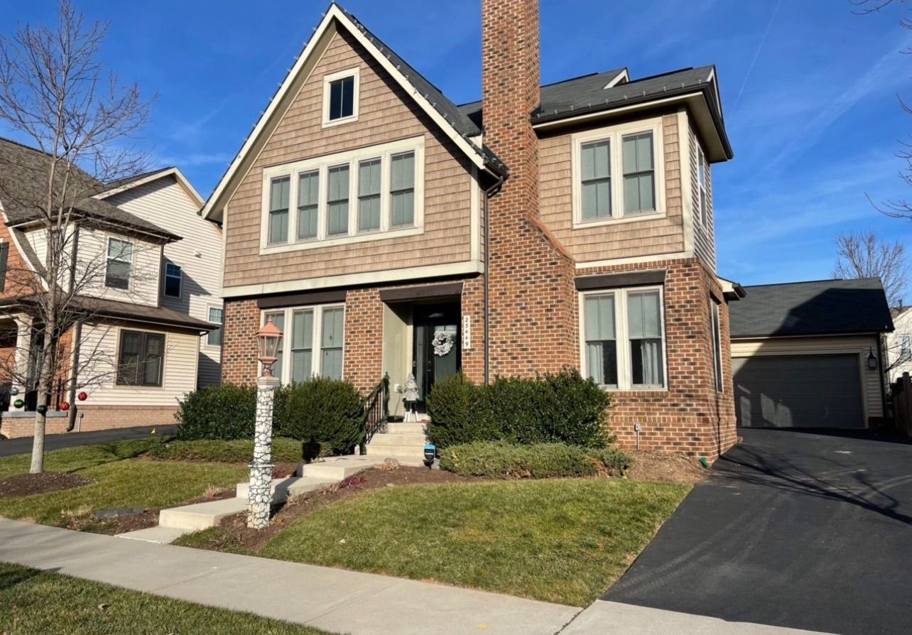A large brick house with a chimney is sitting on top of a lush green lawn.