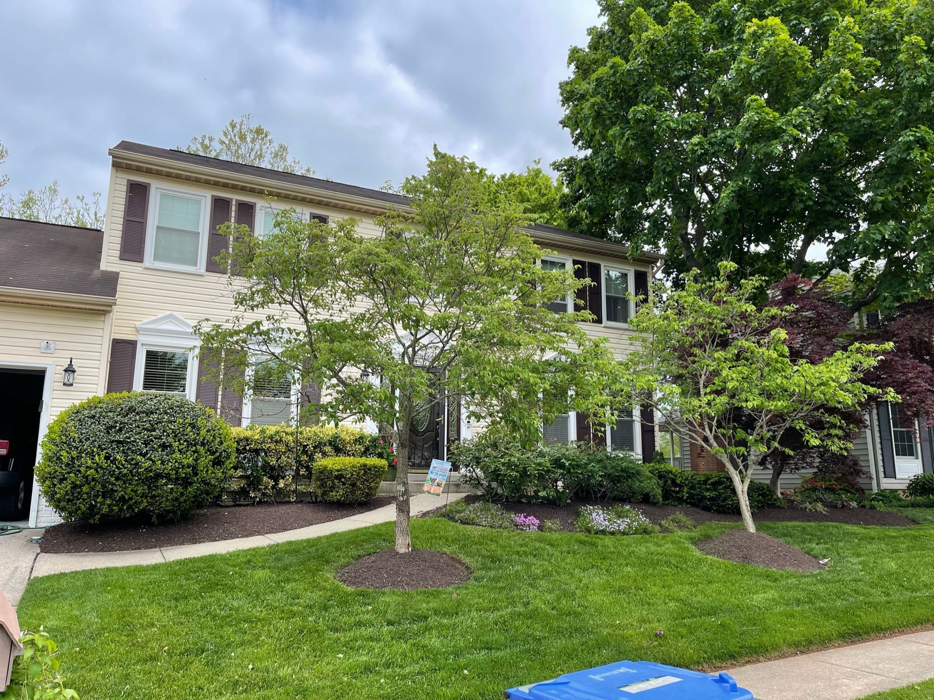 A large house with a lush green lawn and trees in front of it.