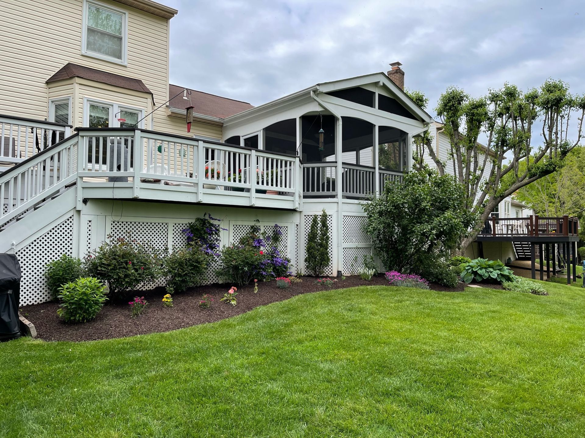A large house with a screened in porch and a large lawn in front of it.