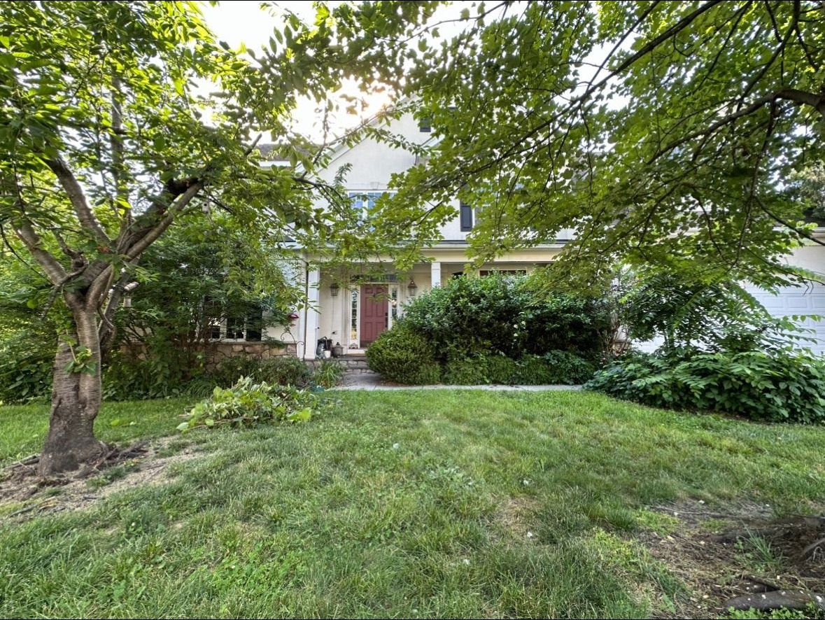 A house with a large lawn and trees in front of it.