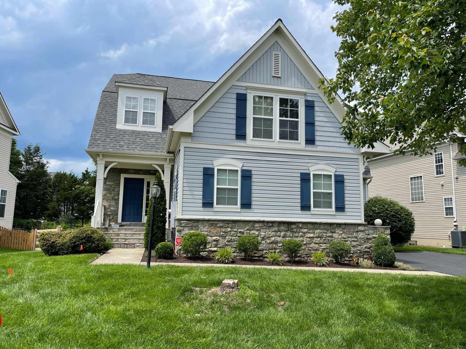 A white house with blue shutters is sitting on top of a lush green lawn.