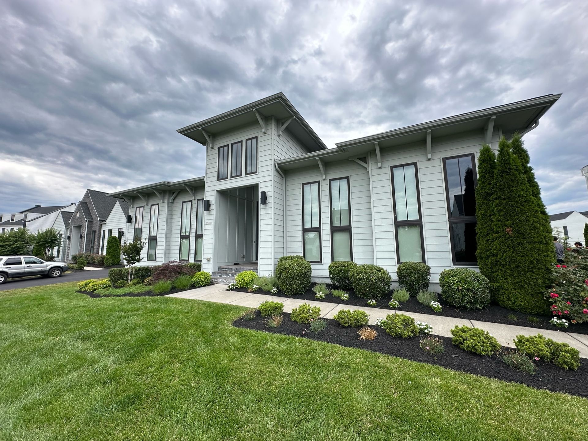 A large white house with a lot of windows is sitting on top of a lush green lawn.