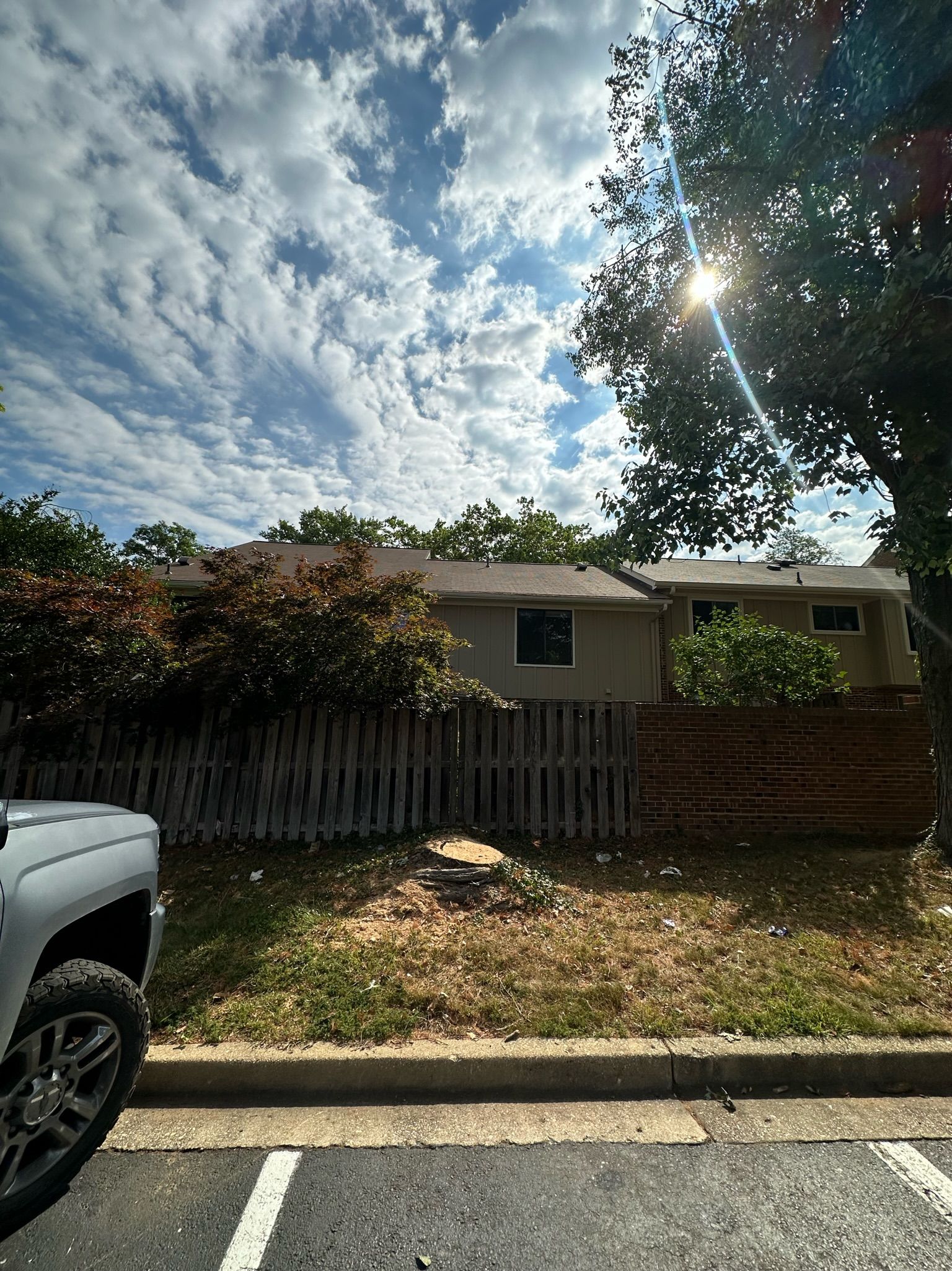 A white truck is parked in a parking lot in front of a house.