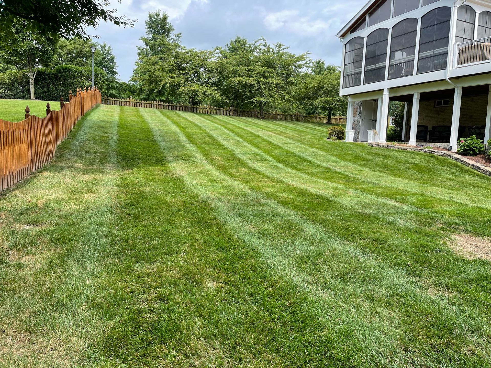 A lush green lawn in front of a house with a screened in porch.