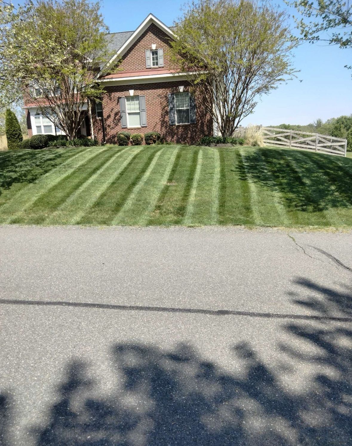 A brick house with a lush green lawn in front of it.