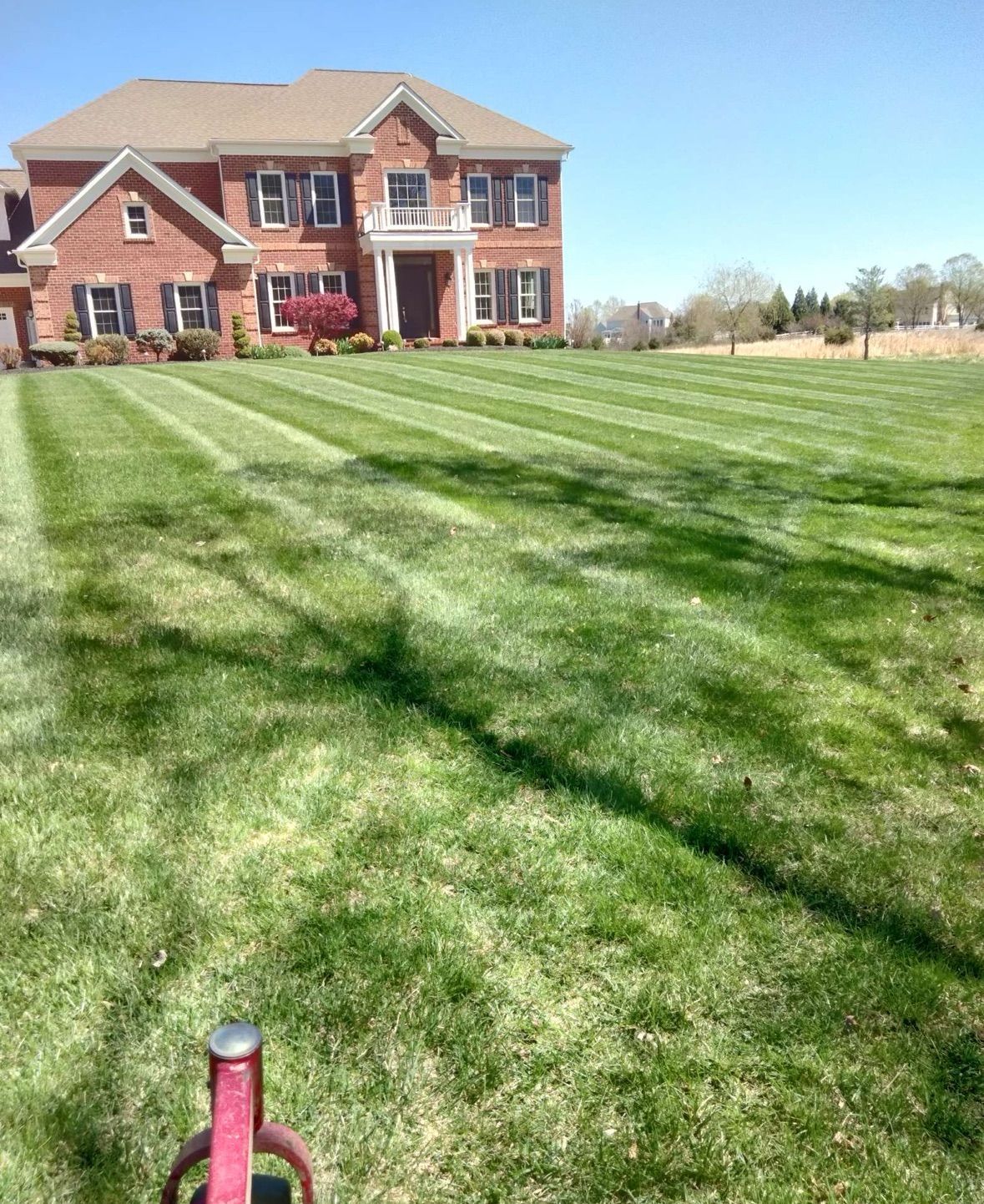 A large brick house with a lush green lawn in front of it.