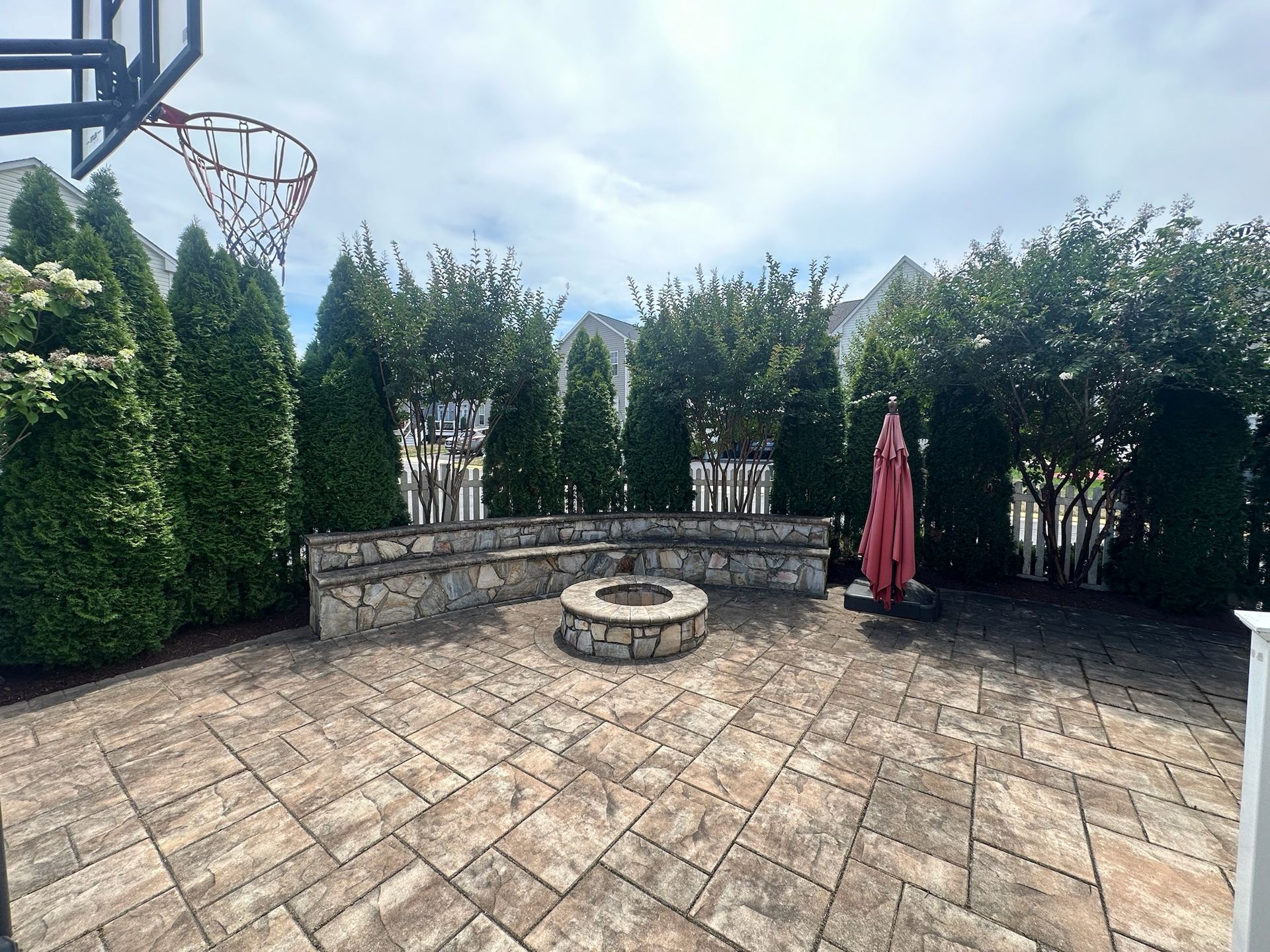 There is a fire pit and a basketball hoop in the backyard.