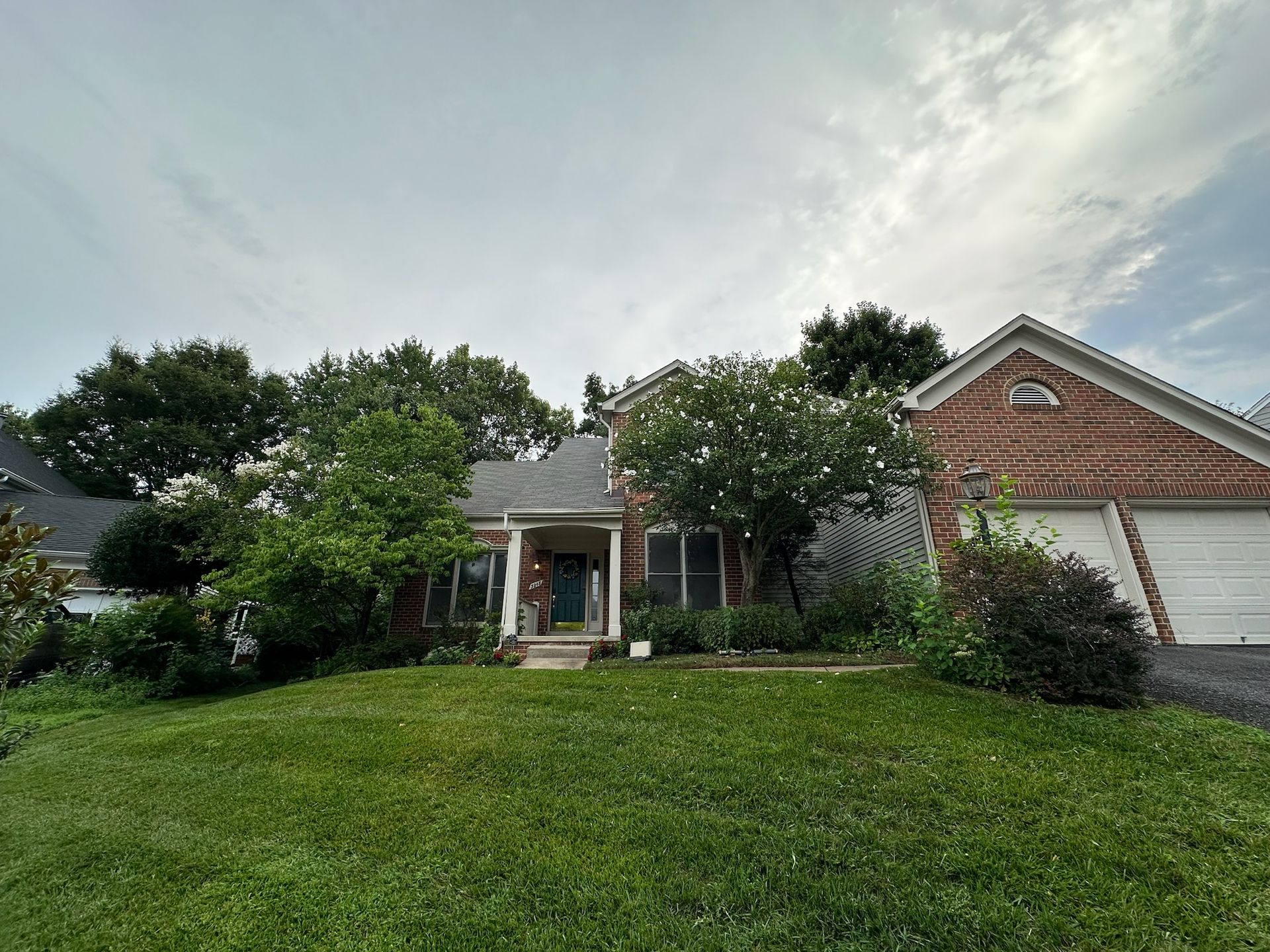 A large brick house with a large lawn in front of it.
