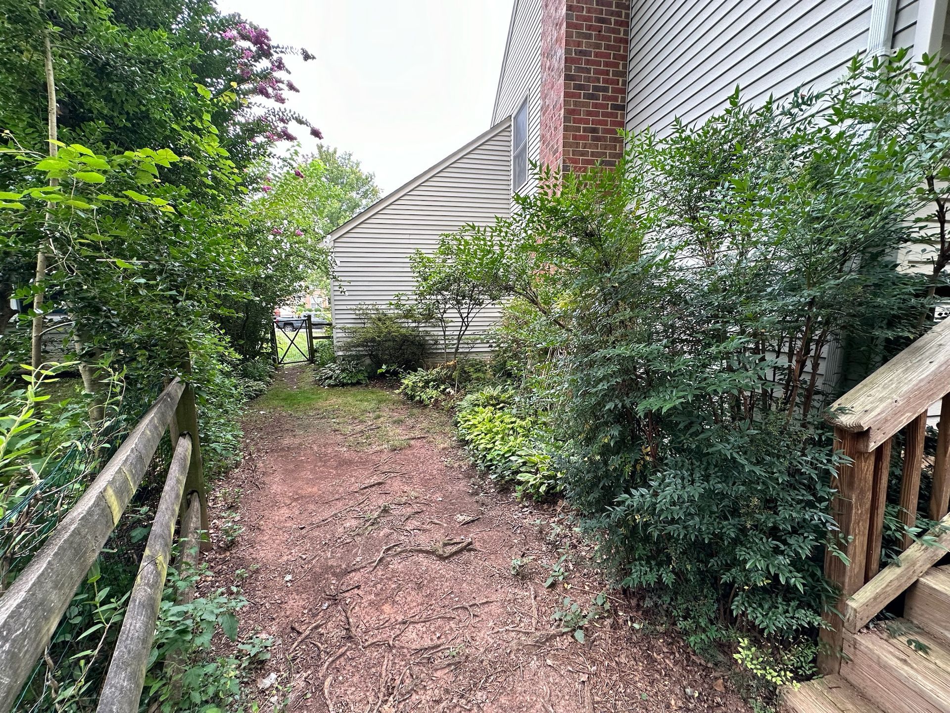 A wooden fence surrounds a dirt path leading to a house.