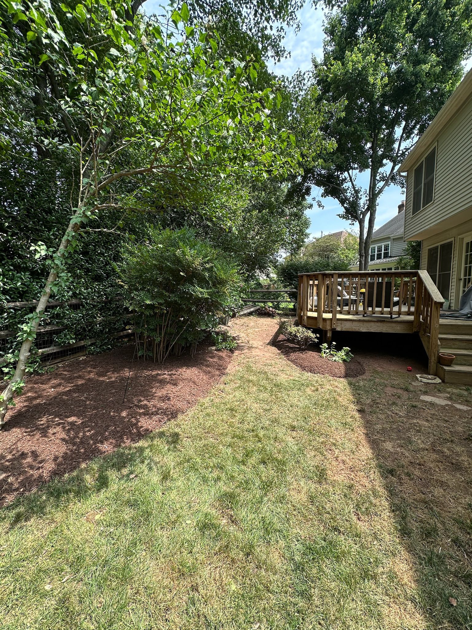 There is a deck in the backyard of a house surrounded by trees.