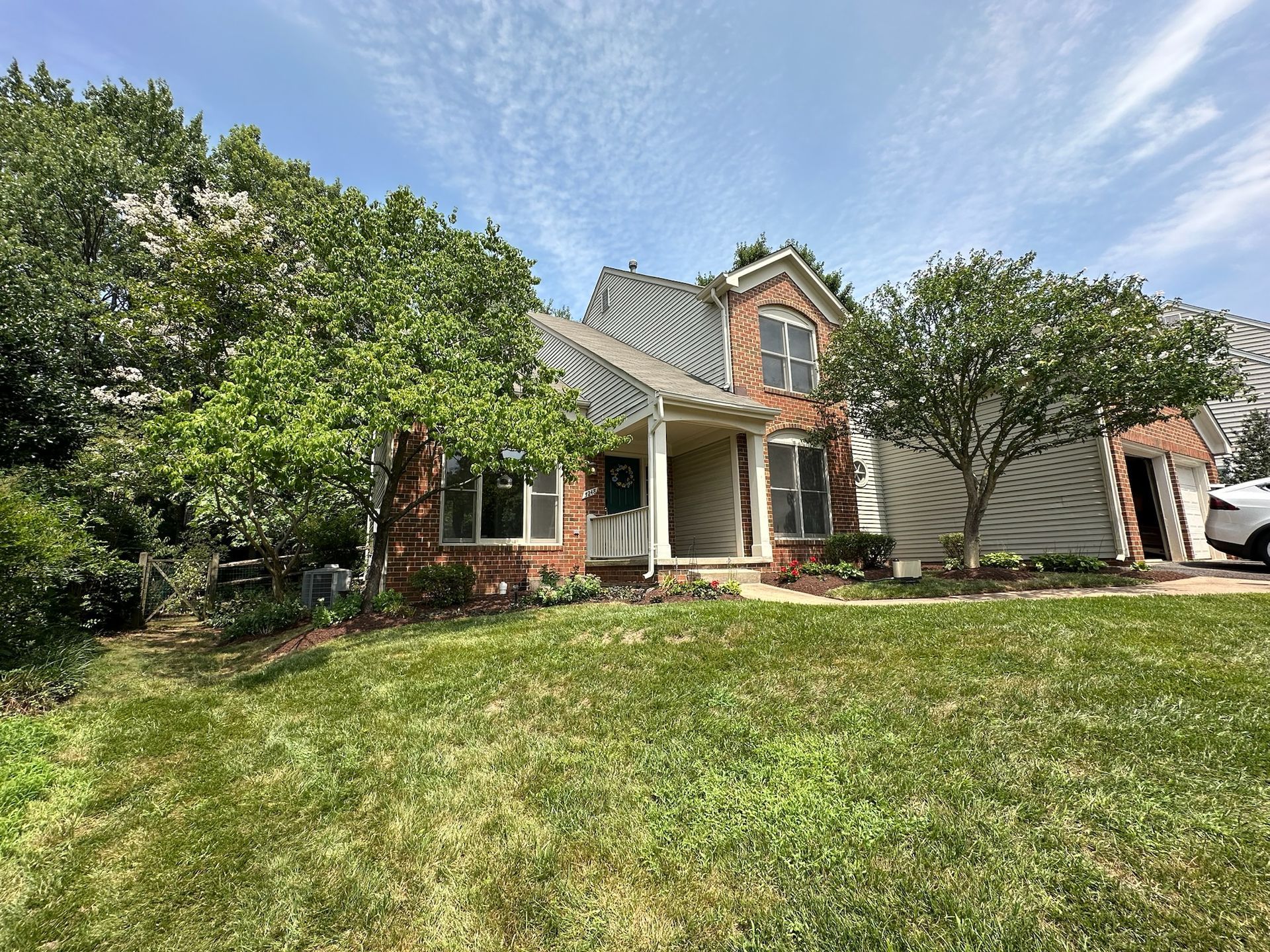 A brick house with a large lawn and trees in front of it.