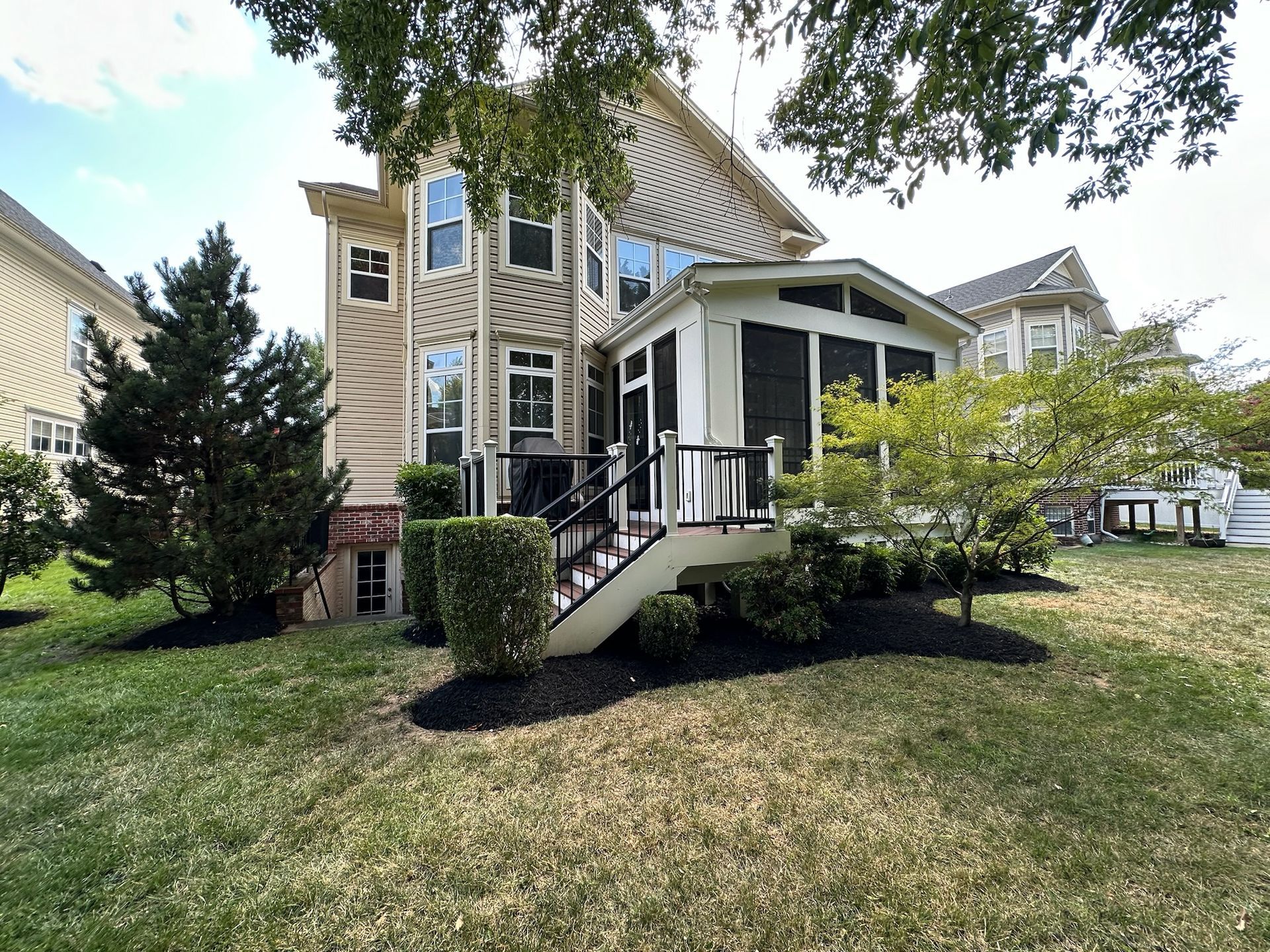 The back of a house with a screened in porch and stairs.