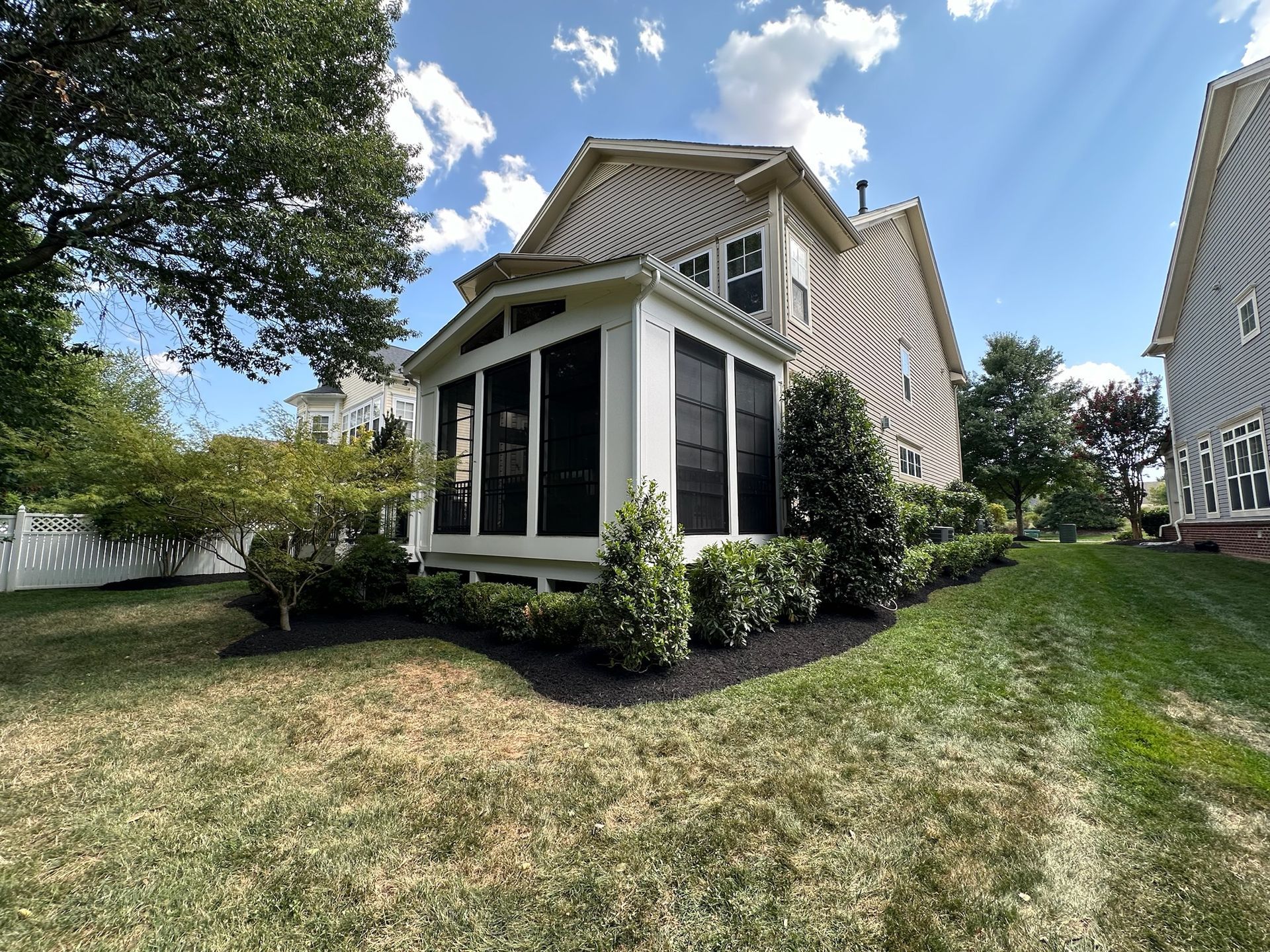 A house with a screened in porch in the backyard.