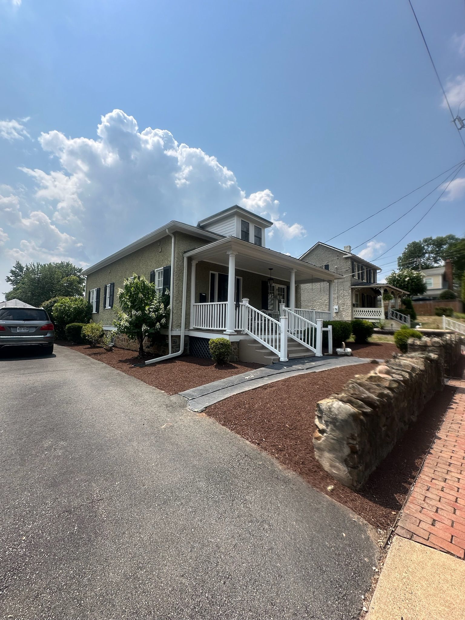 A house with a car parked in front of it on a sunny day.