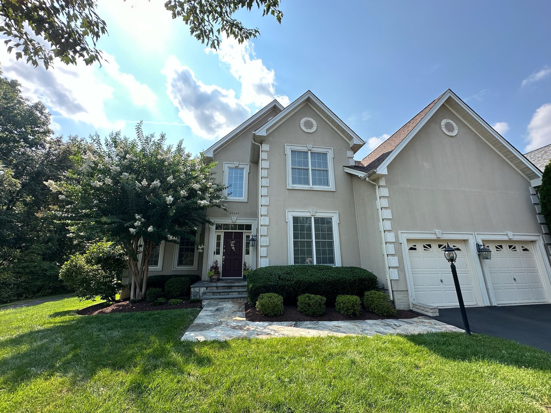A large house with two garages and a lush green yard
