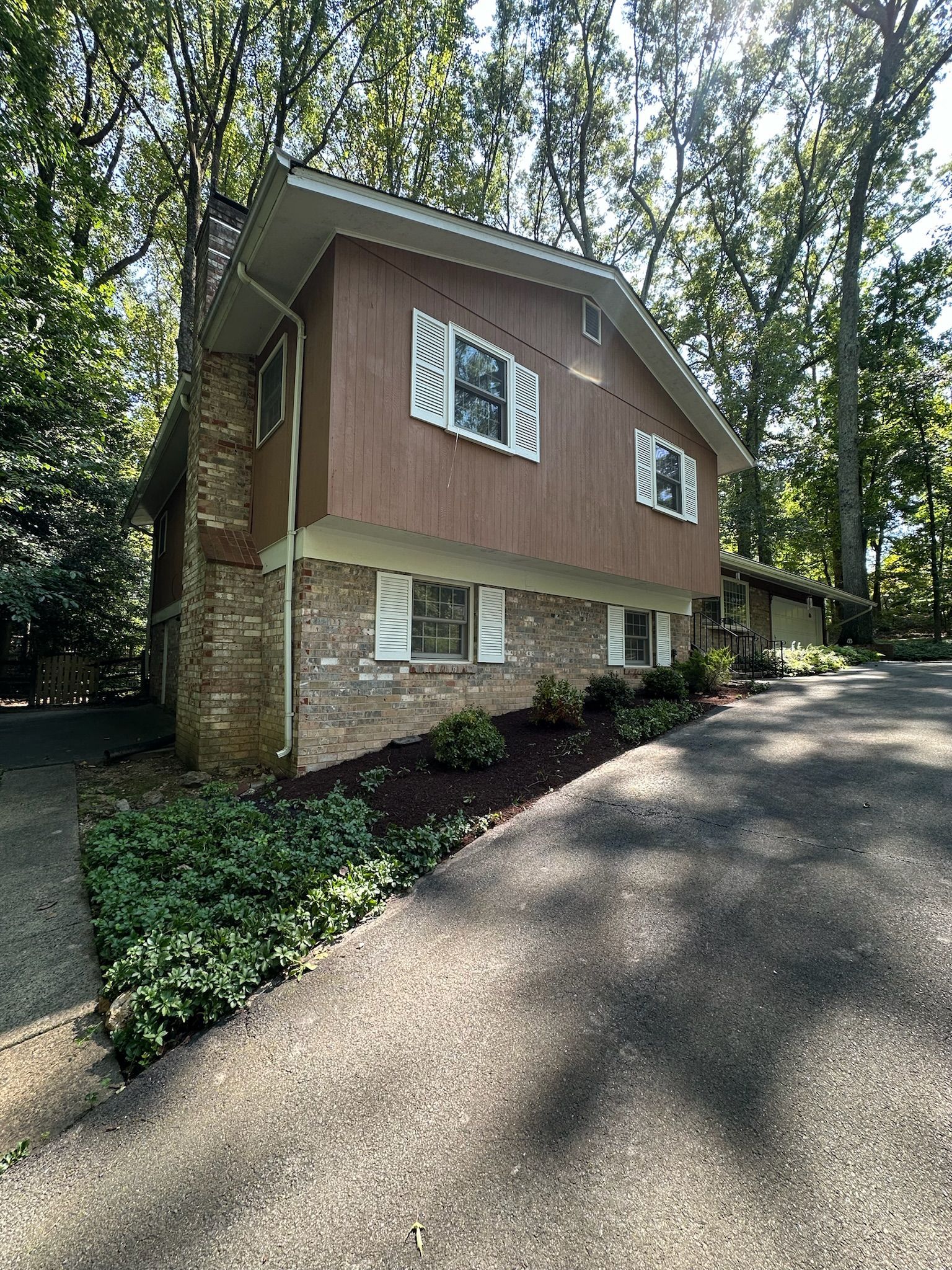 A large house with a driveway leading to it is surrounded by trees.