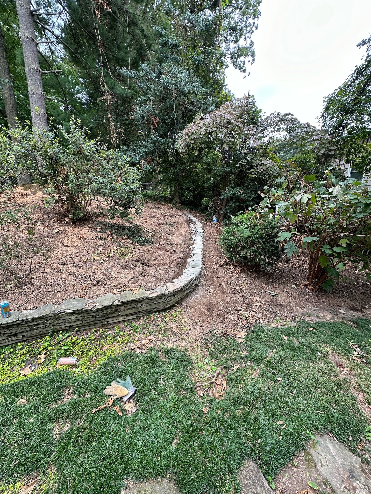 A stone wall is surrounded by trees and grass in a garden.