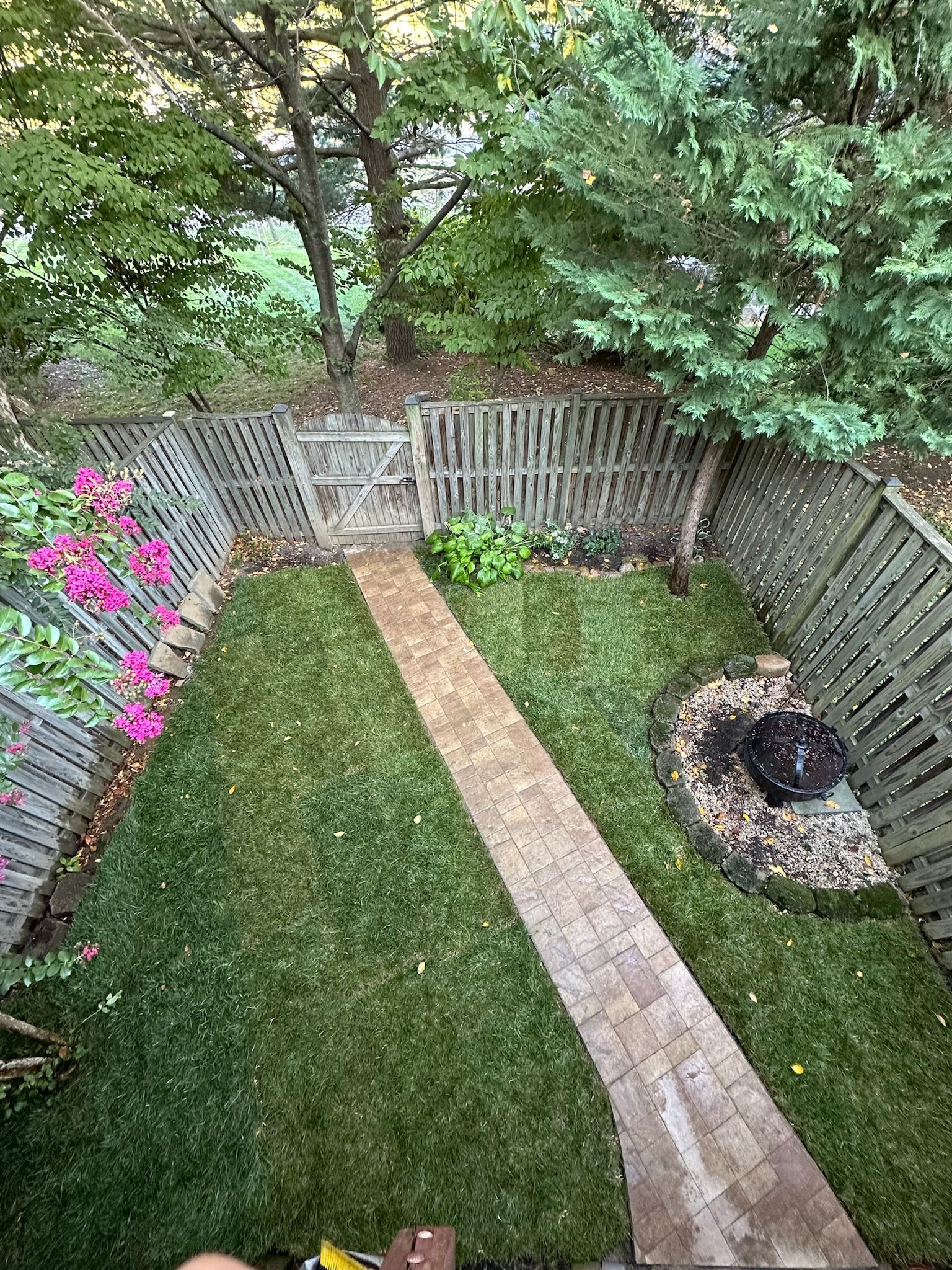 An aerial view of a backyard with a brick walkway and a fire pit.