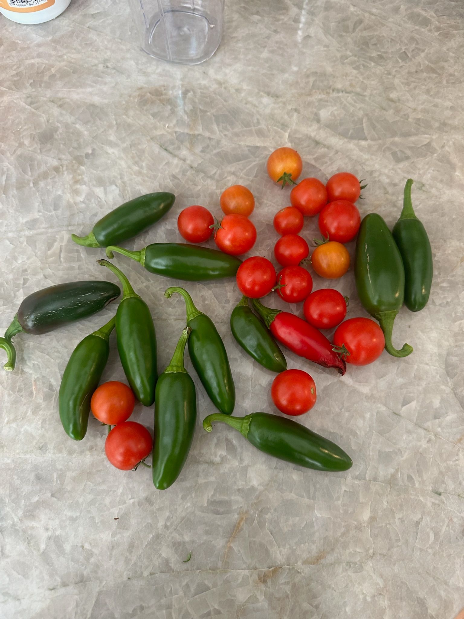 A table topped with tomatoes , jalapenos , and cucumbers.