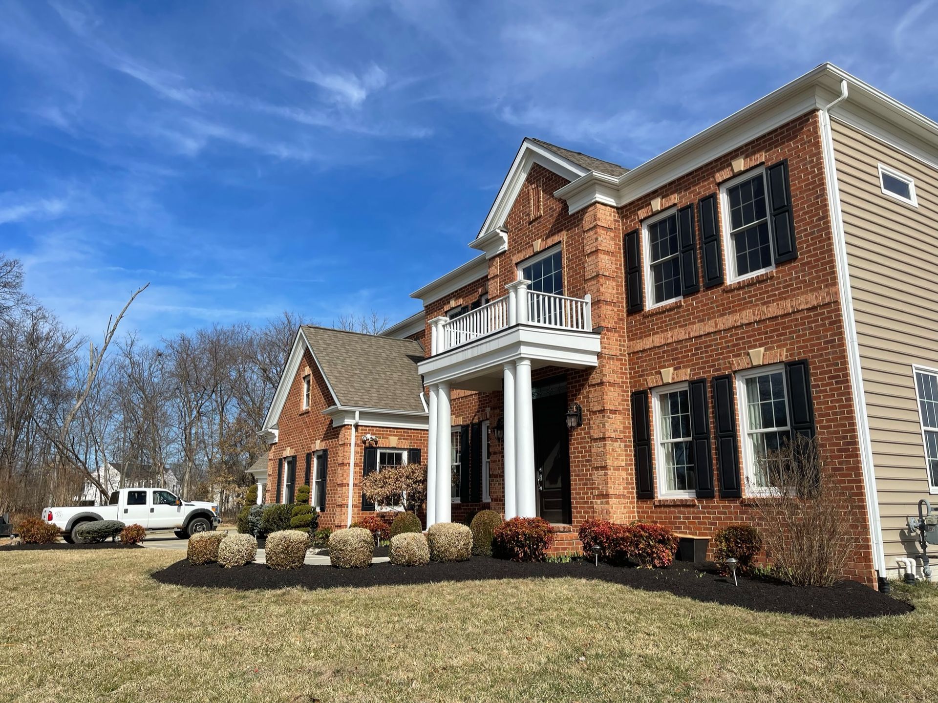 A large brick house with a white truck parked in front of it.