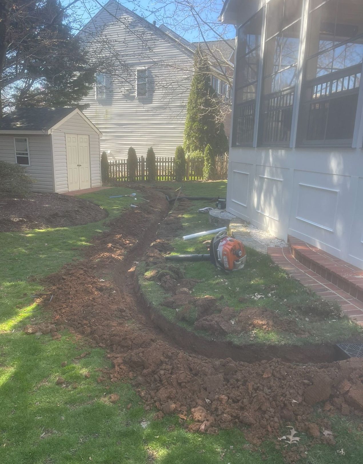 A lawn mower is sitting in the dirt in front of a house.