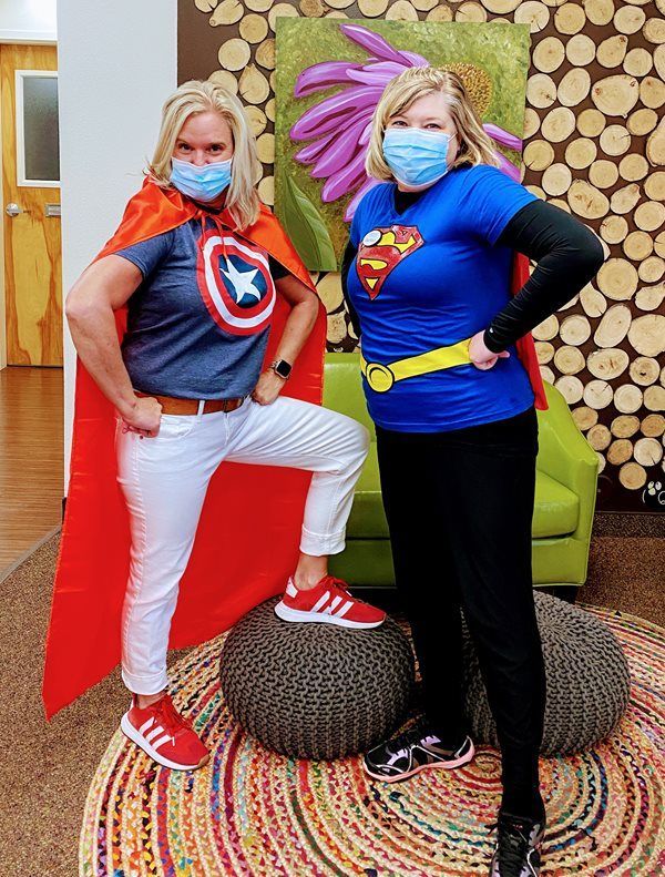 Two women wearing masks and capes are standing next to each other.