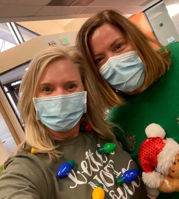 Two women wearing face masks are posing for a picture
