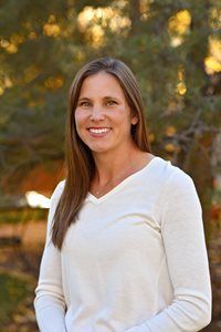 A woman in a white sweater is smiling for the camera.